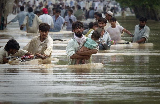 A man wades through waist deep waters with his child while escaping floods in Risalpur, located in Nowshera District, in Pakistan's Northwest Frontier Province July 30, 2010. About 150 people have been killed by flashfloods and bad weather in Pakistan in the last week, with the country's northwest and Baluchistan provinces bearing the brunt of the storms, officials said on Thursday.  REUTERS/Adrees Latif  (PAKISTAN - Tags: DISASTER ENVIRONMENT)